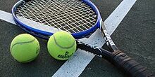 Tennis_Racket_and_Balls Two tennis balls and a tennis racquet lying on a court near white boundary lines.